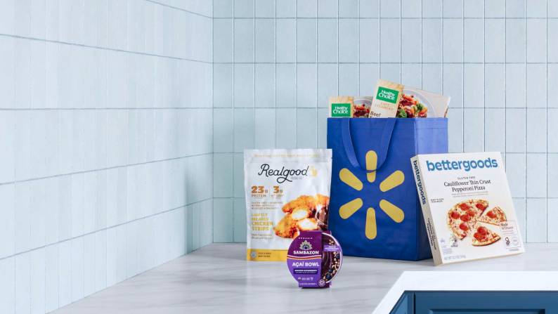 Frozen food & a Walmart reusable bag filled with groceries sitting on a kitchen countertop.
