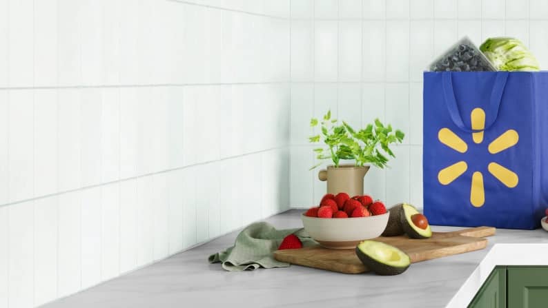 Fresh fruit & a Walmart reusable bag filled with groceries sitting on a kitchen countertop.
